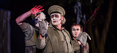 Theaterstück mit 3 Männern, die Weiß geschminkt sind und es spritzt rotes Kunstblut